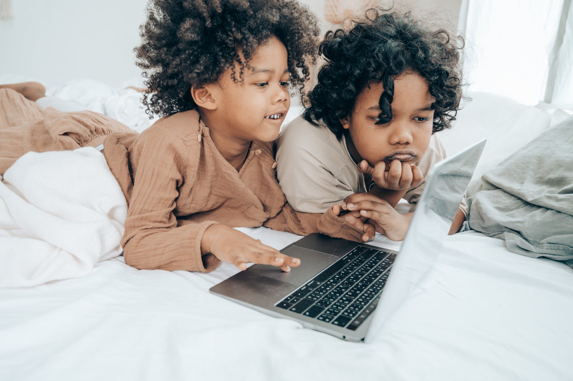 black little brothers browsing internet on laptop in bedroom