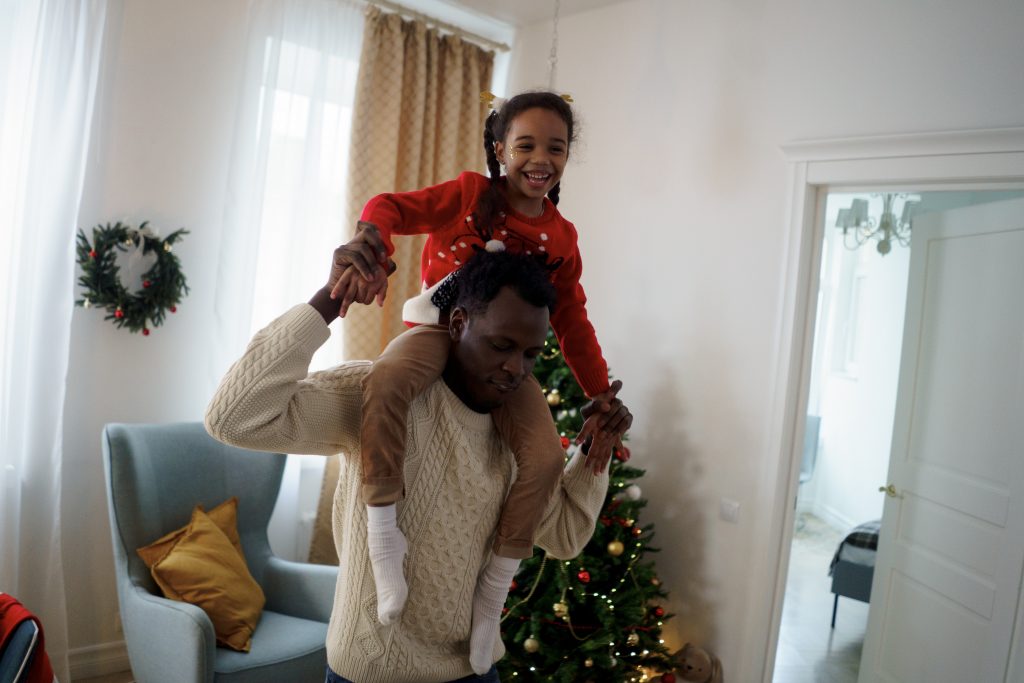 un père et sa fille dansent dans le salon à la période des vacances de Noël